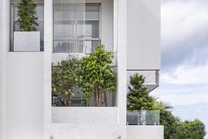 Un edificio moderno con facciata bianca e pulita, ampie finestre e balconi con piante.