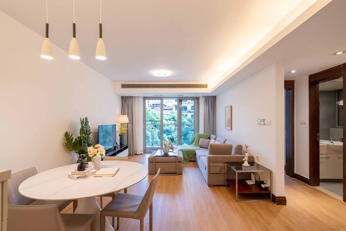 A modern living room with a dining area, a sofa, a coffee table, and a TV.