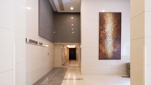 A modern hotel corridor with a checkered floor pattern, a large abstract artwork on the wall, and a sign indicating the hotel name. - Tyms Premium 1BR 1BA Apt Yongxin Century (Shanghai)