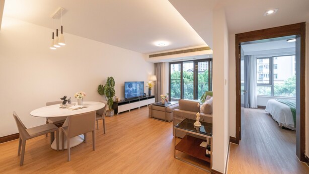 A modern living room with a round dining table, sofas, and a TV. - Tyms Premium 1BR 1BA Apt Yongxin Century (Shanghai)