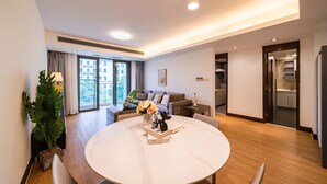 A modern living room with a round dining table, a sofa, and a large window with curtains. - Tyms Premium 1BR 1BA Apt Yongxin Century (Shanghai)