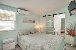Ein Schlafzimmer mit Bett, Nachttisch, Klimaanlage und einem Fenster mit Jalousien.