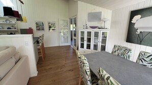 A dining area with a table and chairs, a cabinet with glass doors, and a wall-mounted painting.