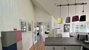 A kitchen with a marble countertop, wooden cabinets, and hanging pendant lights.