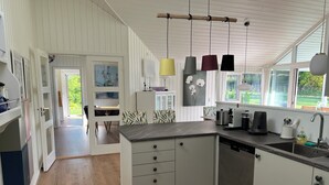 A modern kitchen with a central island, pendant lights, and a view of the outdoors.