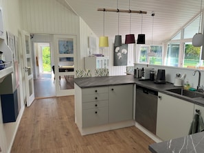 A modern kitchen with a central island, pendant lights, and a view of the outdoors.