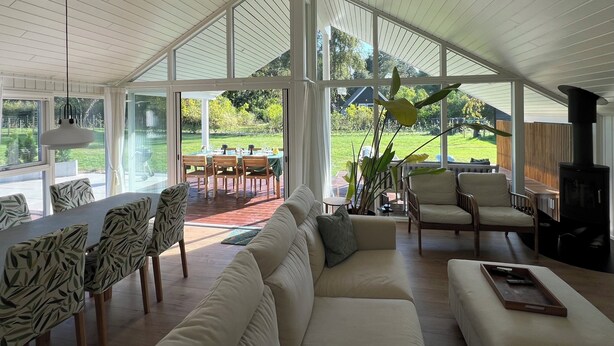 A spacious living area with a large window, a sofa, a dining table, and chairs.