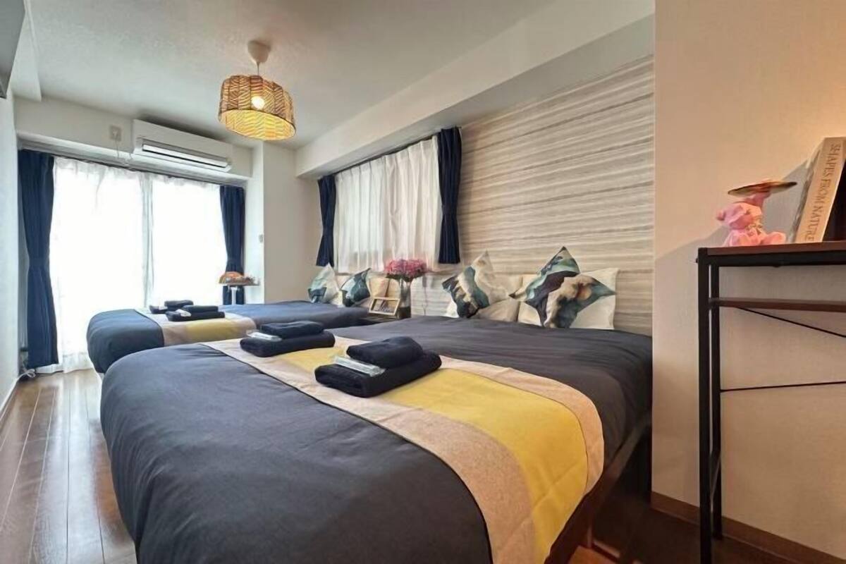 Une chambre d’hôtel avec un grand lit, une table de chevet, un appareil de climatisation, un luminaire suspendu et une fenêtre avec des rideaux.