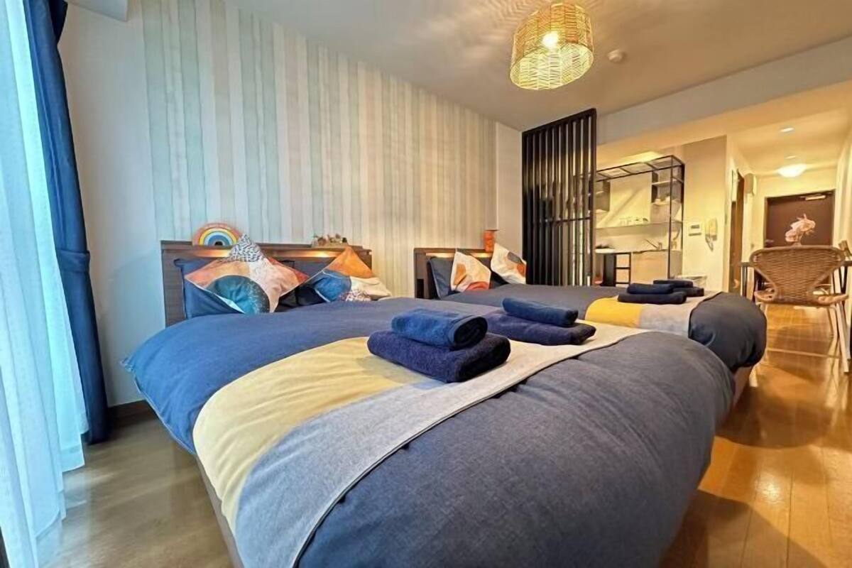 Une chambre d’hôtel moderne avec un grand lit, une table de chevet, un miroir et une lampe en osier.