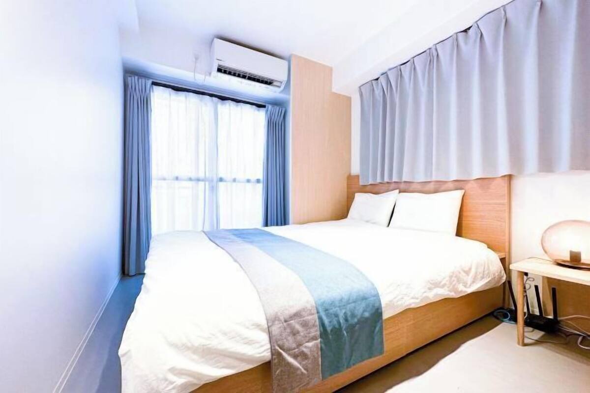 Une chambre d’hôtel avec un grand lit, une table de chevet avec une lampe et une fenêtre avec des rideaux.