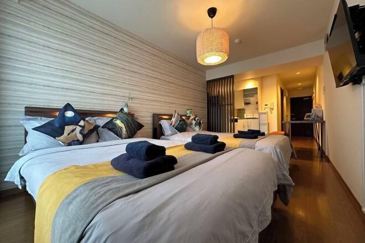 Une chambre d’hôtel avec deux lits, une grande fenêtre, un téléviseur à écran plat et un luminaire moderne.