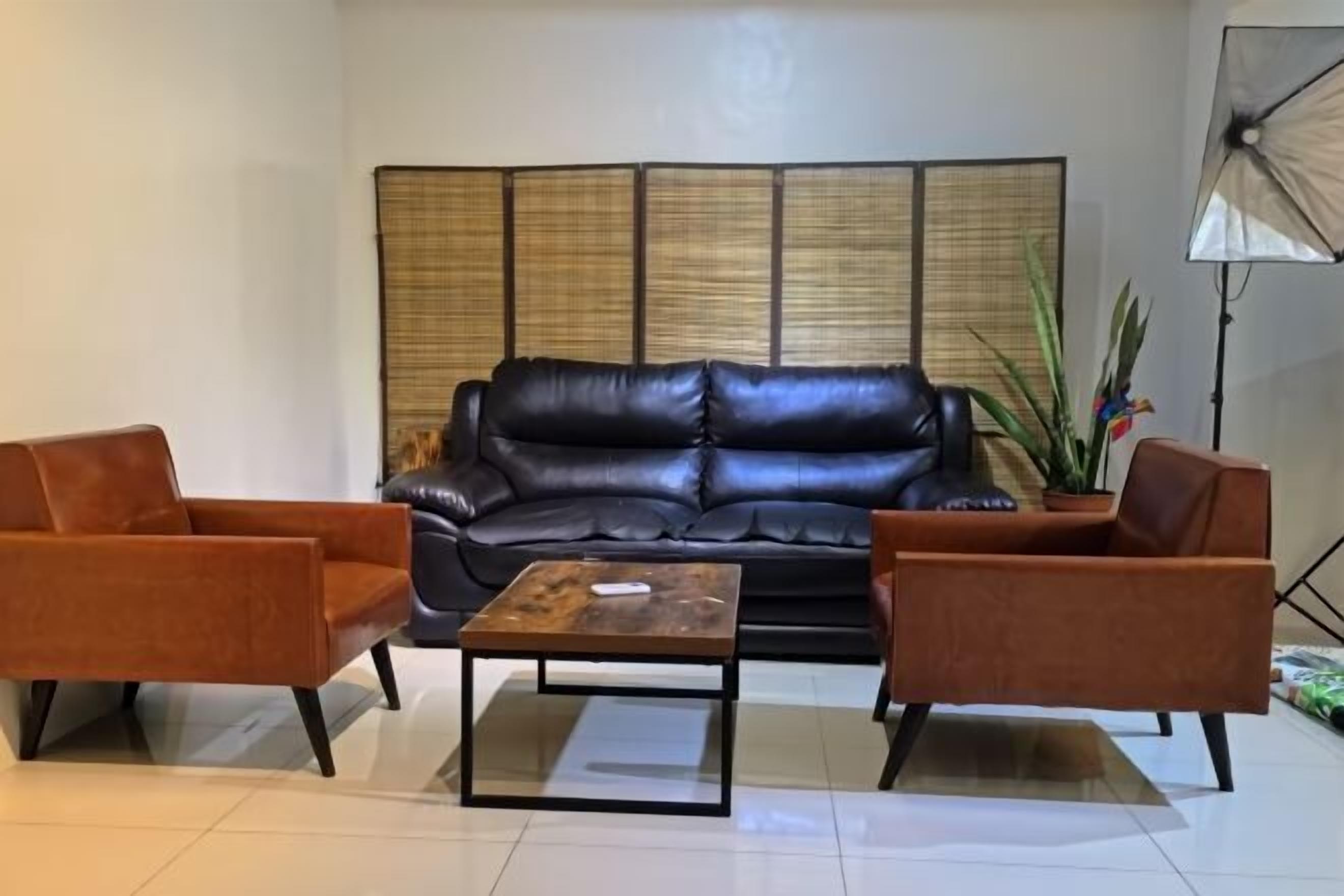 A living room with a black leather sofa, two brown armchairs, and a wooden coffee table.