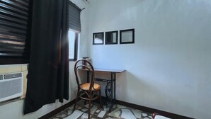 A small room with a desk, chair, and a radiator. There are three framed pictures on the wall.