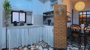 A modern kitchen with white cabinets, a patterned floor, and a dining area with wooden chairs.