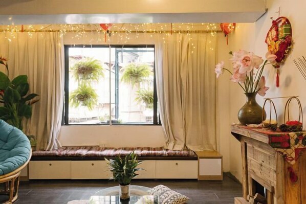 Une pièce chaleureuse avec un coin fenêtre, des plantes en pot et un vase décoratif.