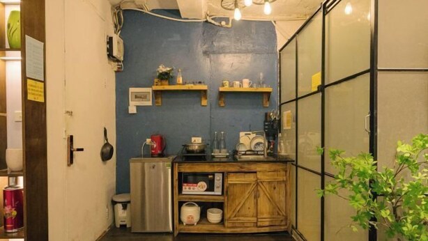 Una cocina estrecha con estantes de madera, una estufa y un refrigerador pequeño.