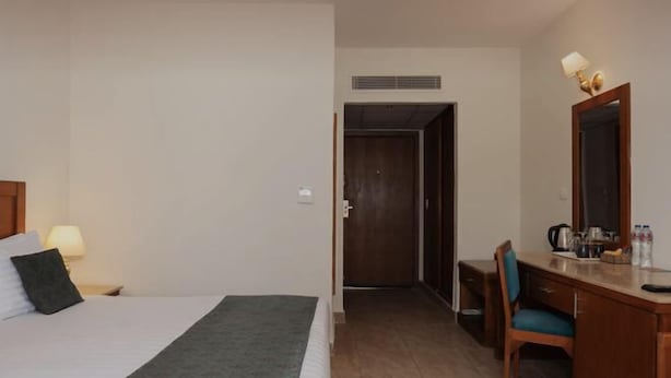 Ein Hotelzimmer mit Bett, Schreibtisch, Stuhl, Spiegel und einer Küchenzeile.