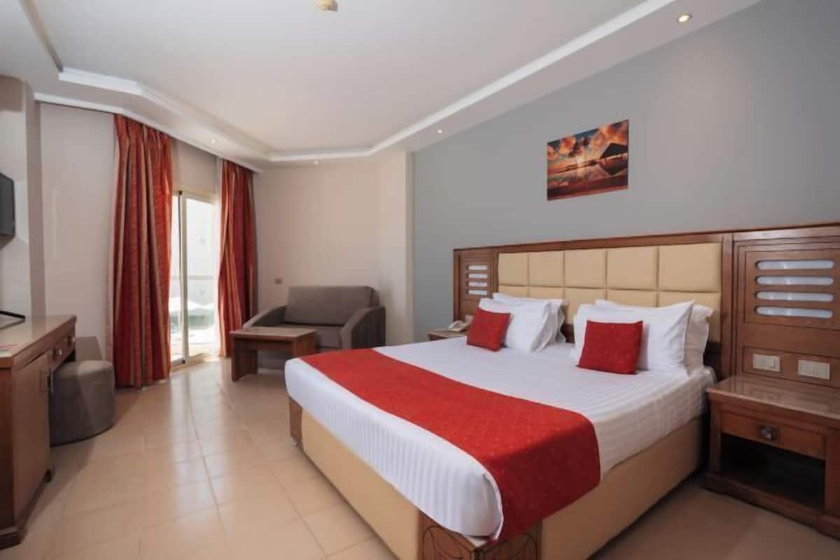 A hotel room with a large bed, a desk, a chair, and a TV.