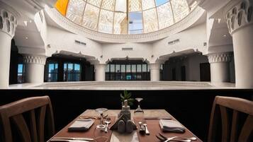 Un interior espacioso con techo alto y área central abierta, que presenta una mesa lista para comer con sillas.