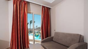 Ein Zimmer mit einer Couch und einem kleinen Tisch, eine Schiebetür zu einem Poolbereich.