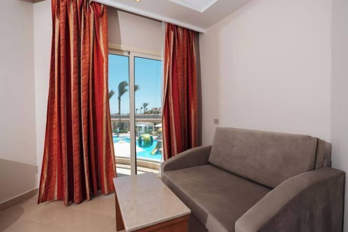 A room with a sofa and a small table, a sliding glass door leading to a pool area.