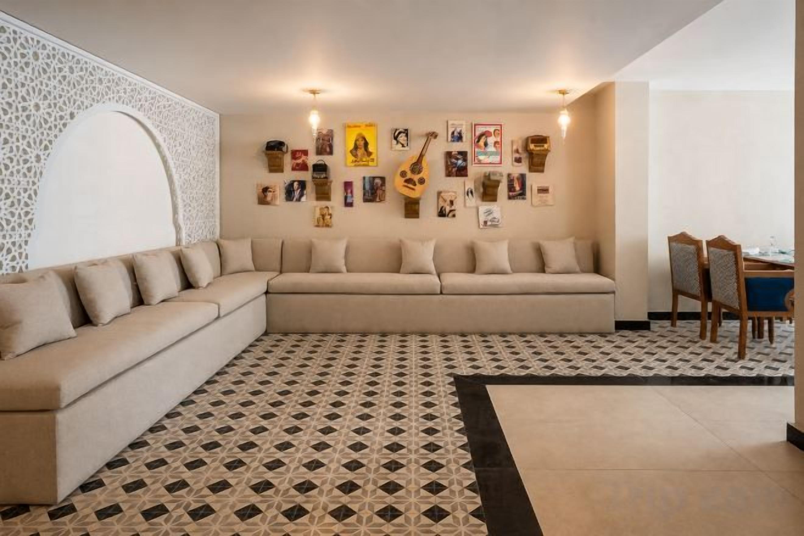 A living room with a beige sectional sofa, patterned rug, and wall art.