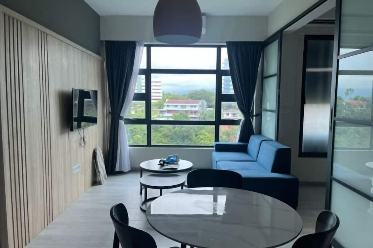 Ein modernes Zimmer mit einer Couch, einem runden Tisch und einem an der Wand befestigten Fernseher.
