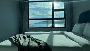Une chambre avec une grande fenêtre, un lit et des rideaux.