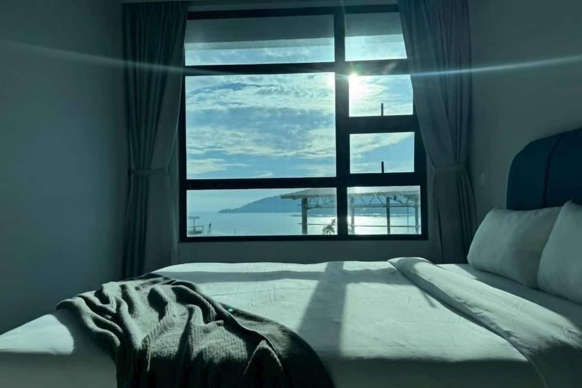 Ein Schlafzimmer mit großem Fenster, einem Bett und Vorhängen.