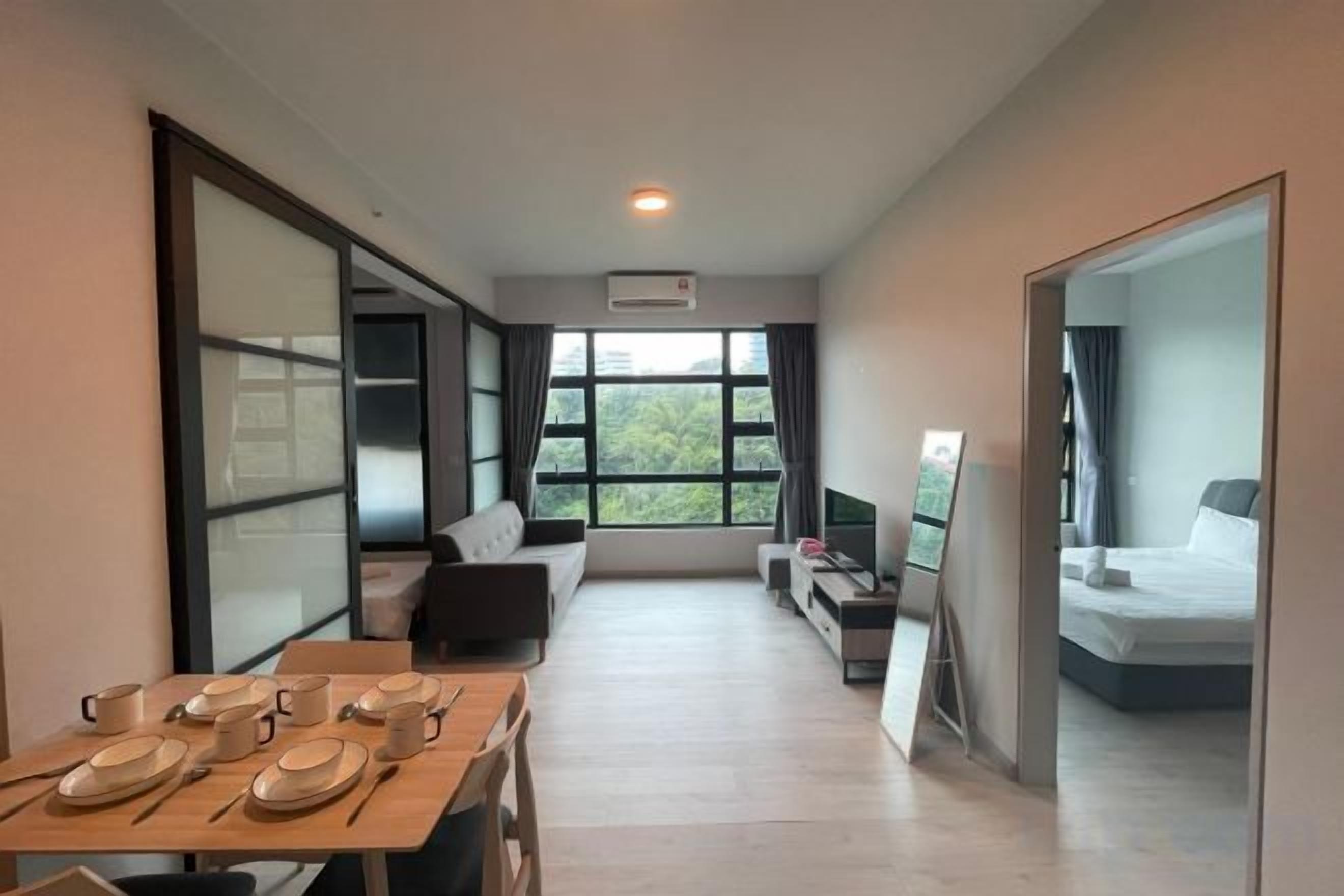 A modern hotel room with a dining area, a sofa, a bed, and a TV.
