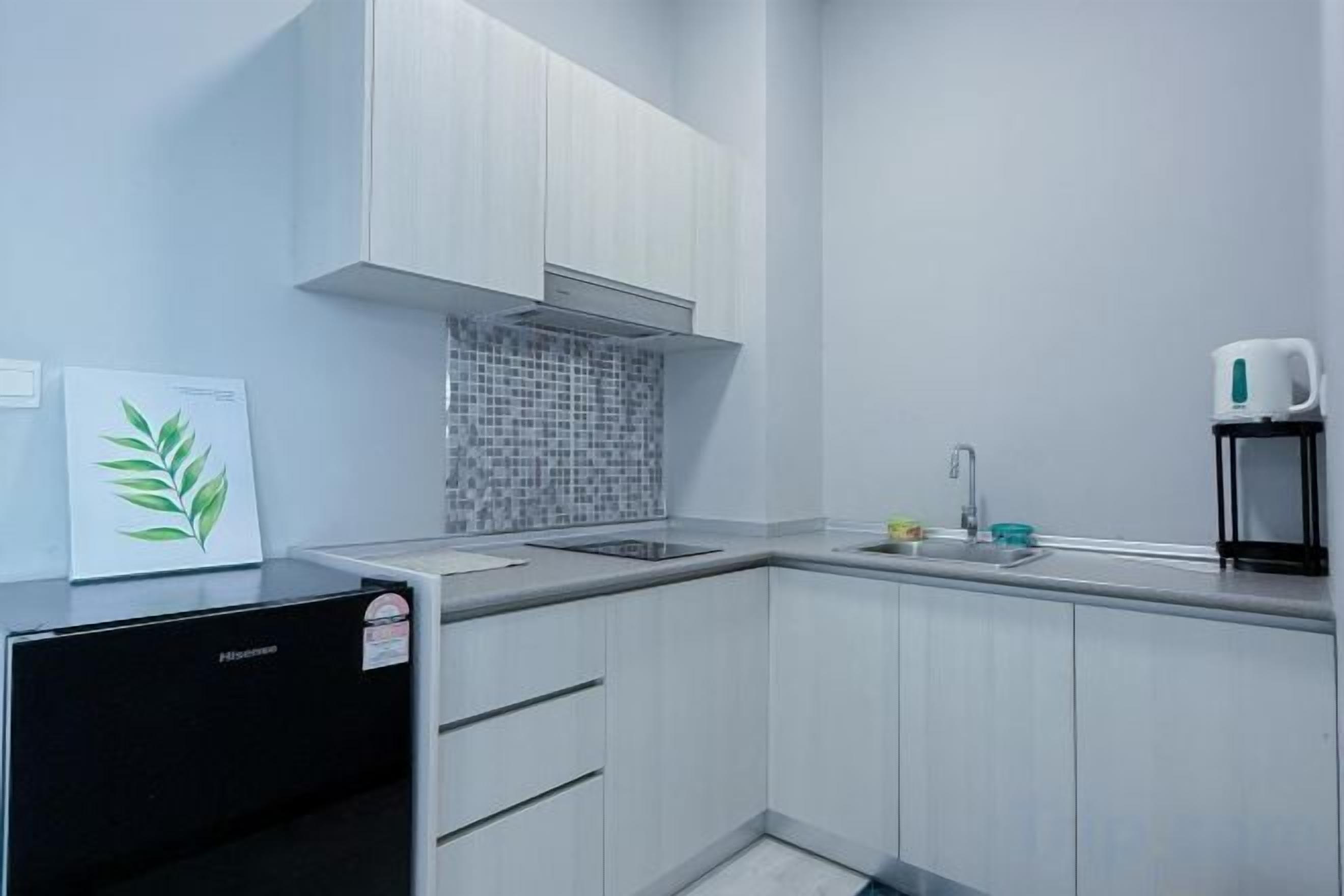Cozinha moderna com armários brancos, geladeira preta, painel de azulejos e máquina de café.