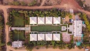 An aerial view of a property with a central courtyard, multiple rooms with triangular roofs, a swimming pool, and a parking area. - Madho Bagh (Sawai Madhopur)