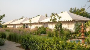 A row of traditional tents with a garden in the foreground. - Madho Bagh (Sawai Madhopur)