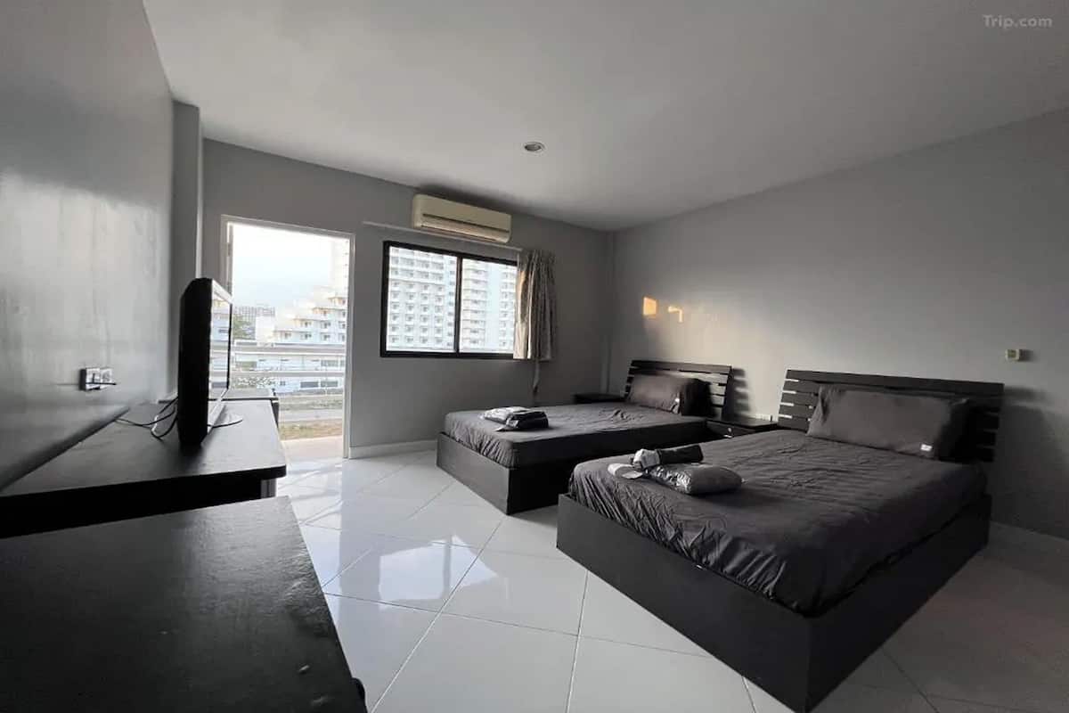 Une chambre d’hôtel moderne avec deux lits, un bureau et une grande fenêtre donnant sur la ville.