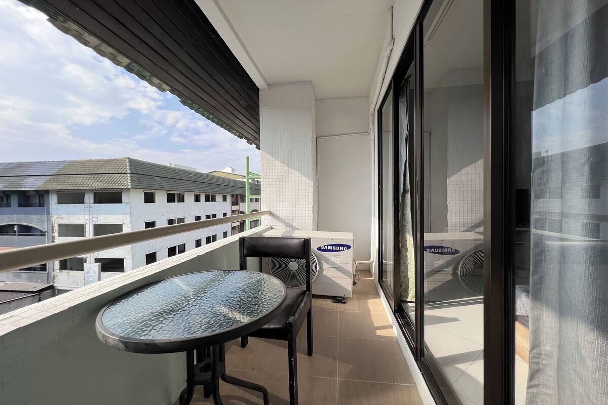 Un balcon avec une table et des chaises, un climatiseur Samsung et une vue sur les bâtiments en arrière-plan.