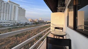 A balcony with a table and chairs, overlooking a road and buildings. - Emerald Hotel Chonburi (Pattaya)