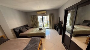 A hotel room with two beds, a TV, and a balcony with curtains. - Emerald Hotel Chonburi (Pattaya)