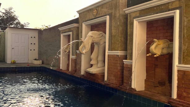 A swimming pool with decorative elephant statues on the walls. - Emerald Hotel Chonburi (Pattaya)