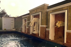 Une piscine dont les murs sont ornés de statues d’éléphants décoratives.
