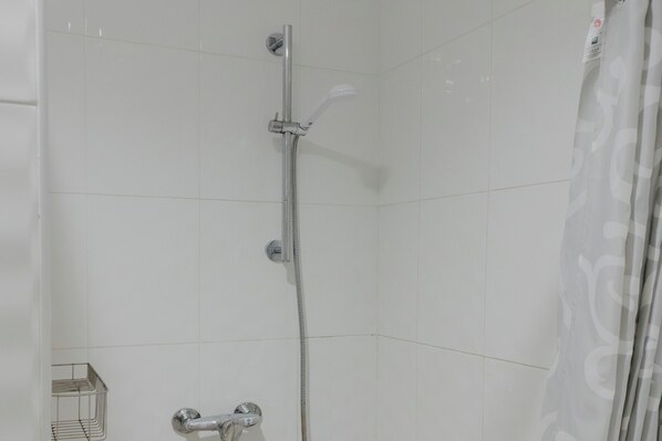Une douche équipée d’un pommeau de douche à main et d’un robinet mural.