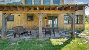 A wooden cabin with a covered patio, outdoor seating, and a door with a green frame. - Unplug, Unwind & Explore: Remote Vermont Cabin (Sharon)