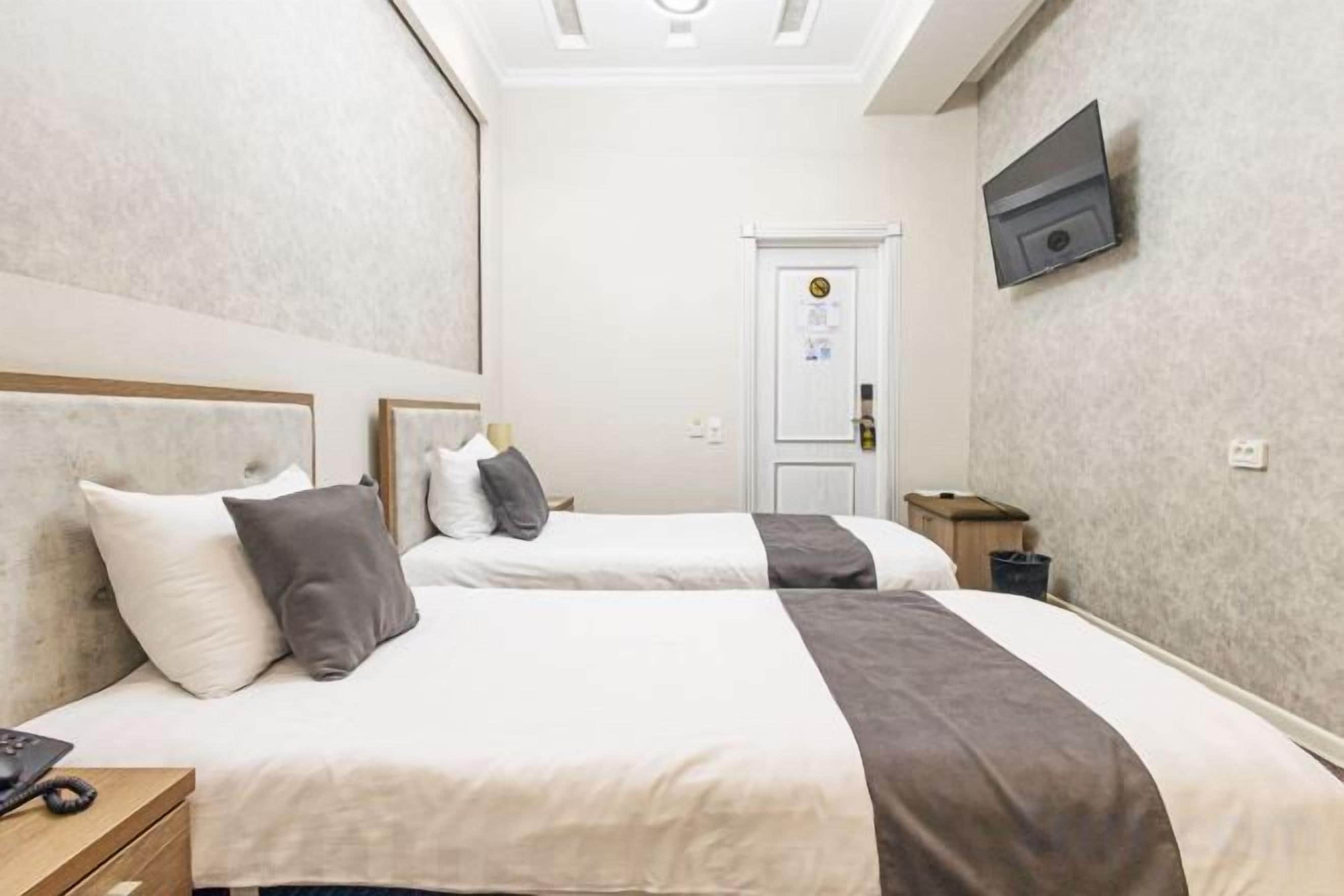 A hotel room with two beds, a television, and a door with a lock.