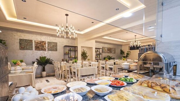Un comedor moderno con varias mesas, una cocina al fondo y diferentes platos sobre las mesas.