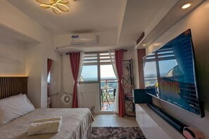 Et hotelværelse med seng, fjernsyn, balkon med udsigt og aircondition.