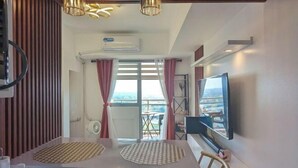 Una camera moderna con un tavolo in vetro, due sottopiatti intrecciati, una TV a schermo piatto e vista sull'esterno.