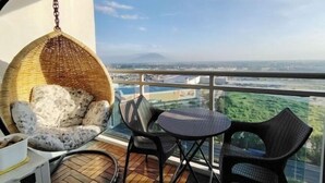 Un balcone con mobili in vimini, una sedia a dondolo e un tavolino.