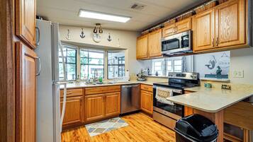 A kitchen with wooden cabinets, a stainless steel refrigerator, a microwave, an oven, and a dishwasher.