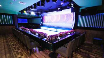 Een bar met een lange toonbank, meerdere stoelen en een podium met verlichting.
