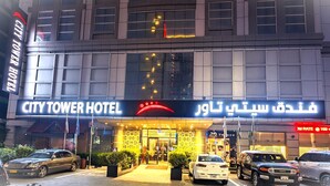 Das Hotel City Tower mit auffälliger Beschilderung, mehreren Flaggen und geparkten Autos.