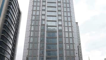 Een hoog hotelgebouw met een moderne gevel van glas, een opvallend bord met de tekst 'CITY TOWER HOTEL' en een drukke straat ervoor.
